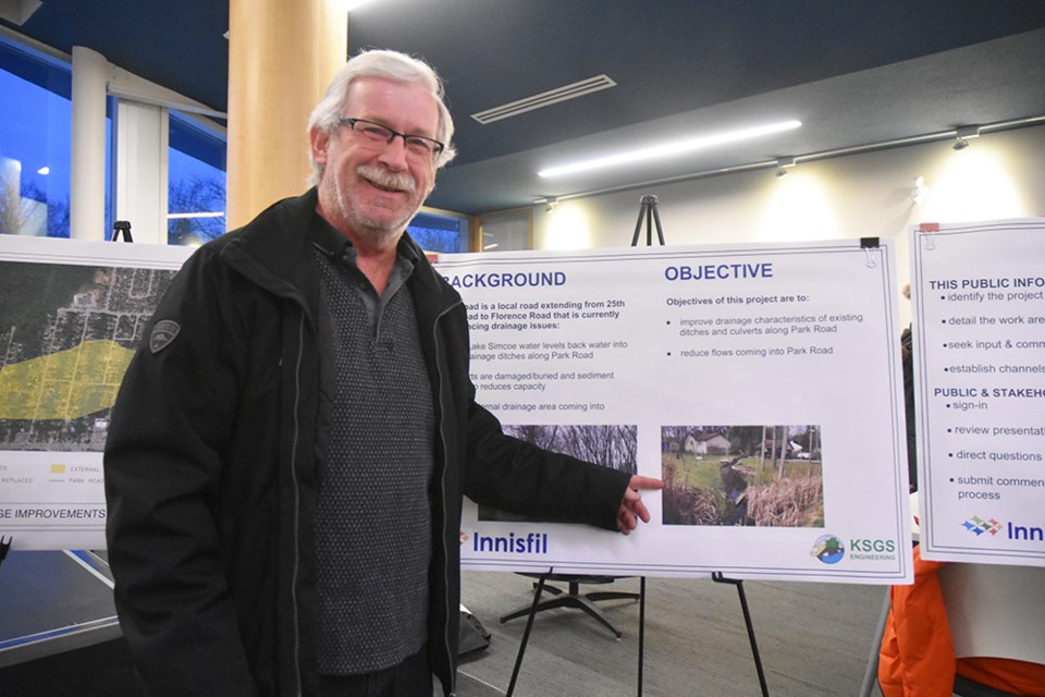 Homeowner Ken Baird points to a photo of his property on Park Road, where an intermittent creek, flowing from Innisfil Beach Park, causes frequent flooding. Miriam King/Bradford Today