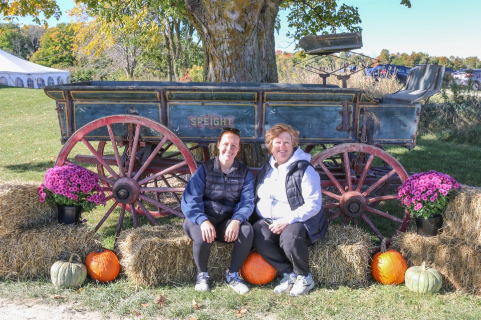 Emilee and Linda MacLean take a seat by the old wagon