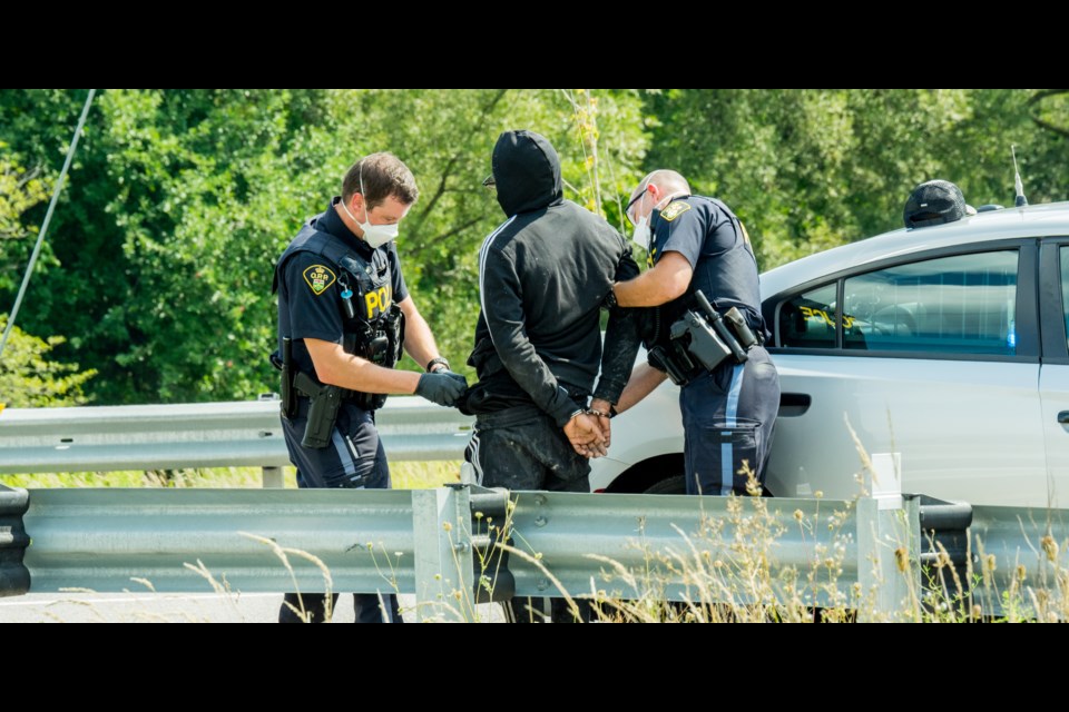 A man is searched after what appeared to be a handgun was retrieved from the creek under the bridge where the two were originally detained. Paul Novosad for Bradford Today.