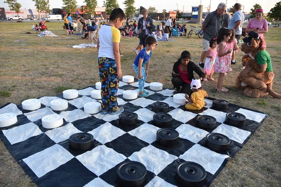 People attending Thursday night's Outdoor Movies night play a game of giant checkers with Furry Friend while waiting for dusk to fall. Miriam King/Bradford Today