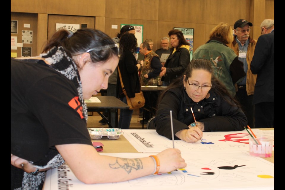 Artist Christi Belcourt painting one of her water protector stencils with a volunteer. Submitted photo/Anna Bourgeois