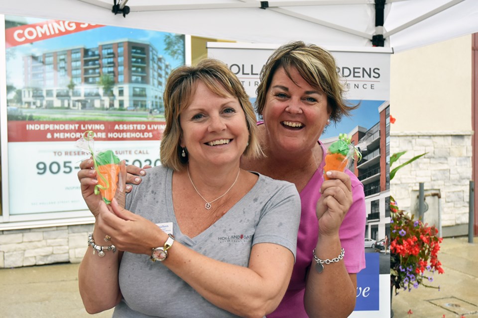 Shelley Snoulten, left, and Melissa McKee of Holland Gardens Retirement Residence hand out carrot-shaped cookies, created by a Verve Senior Living chef. Miriam King/BradfordToday