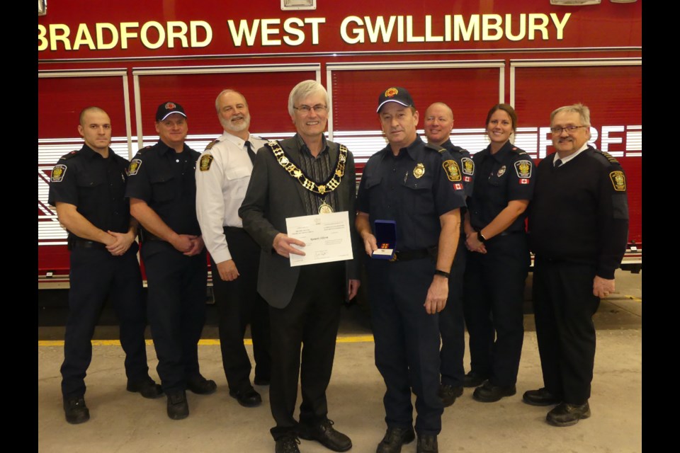 BWG Mayor Rob Keffer presents Ken Sikkema with a certificate, flanked by a group of firefighters, Deputy Chief Olaf Lamerz and Chief Kevin Gallant. Jenni Dunning/BradfordToday