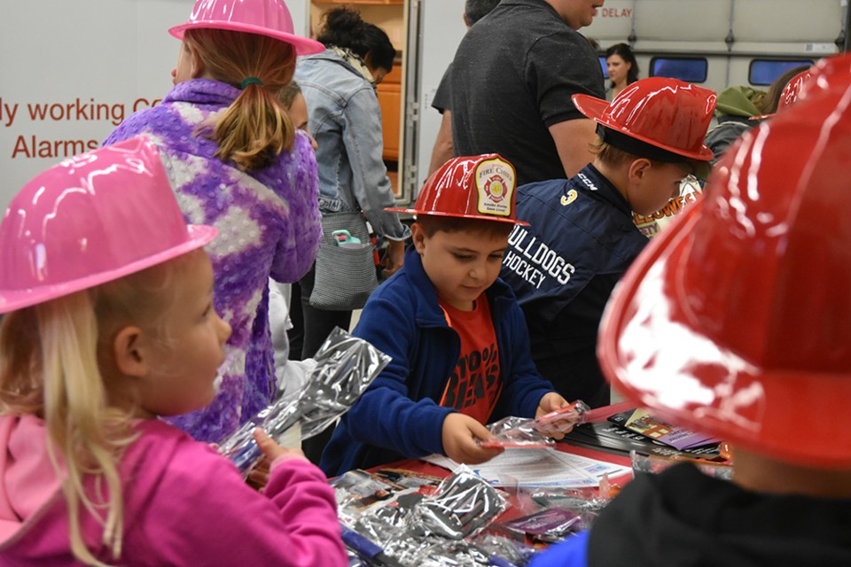 Junior Fire Chiefs crowd around to pick up give-aways that included reflective loot bags for Halloween. Miriam King/Bradford Today