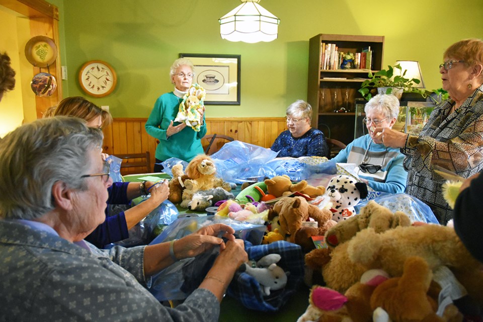 Leila Lloyd, president of the Bond Head Women's Institute (centre) demonstrates how to wrap a stuffed animal in a blanket, to an assembly line of women. Miriam King/Bradford Today