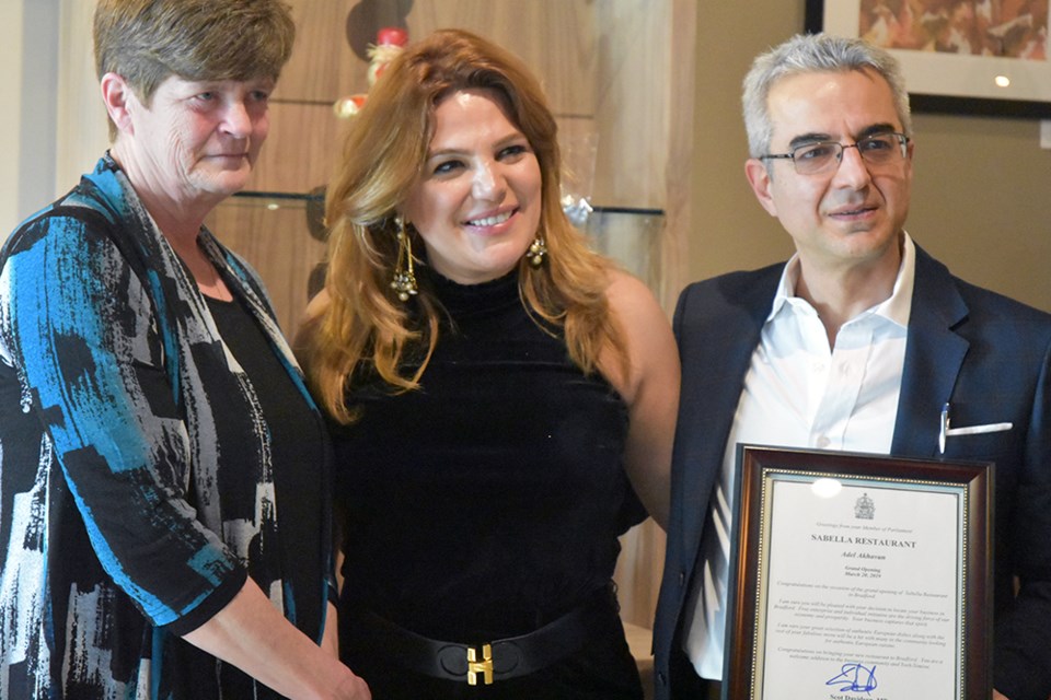 From left, Carol Collier presents certificate from MP Scot Davidson, congratulating Sabella owners Sahar Amini and Adel Akhavan. Miriam King/Bradford Today