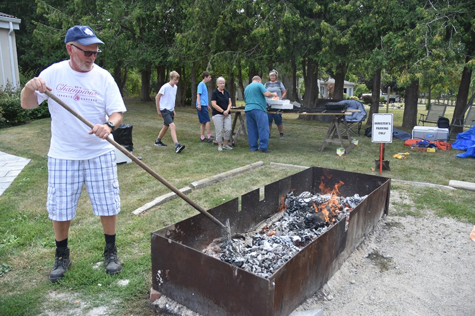 Dave Hamilton carries on a family tradition, preparing the coals for the outdoor Pork Chop Barbecue at Bond Head United Church. Miriam King/Bradford Today
