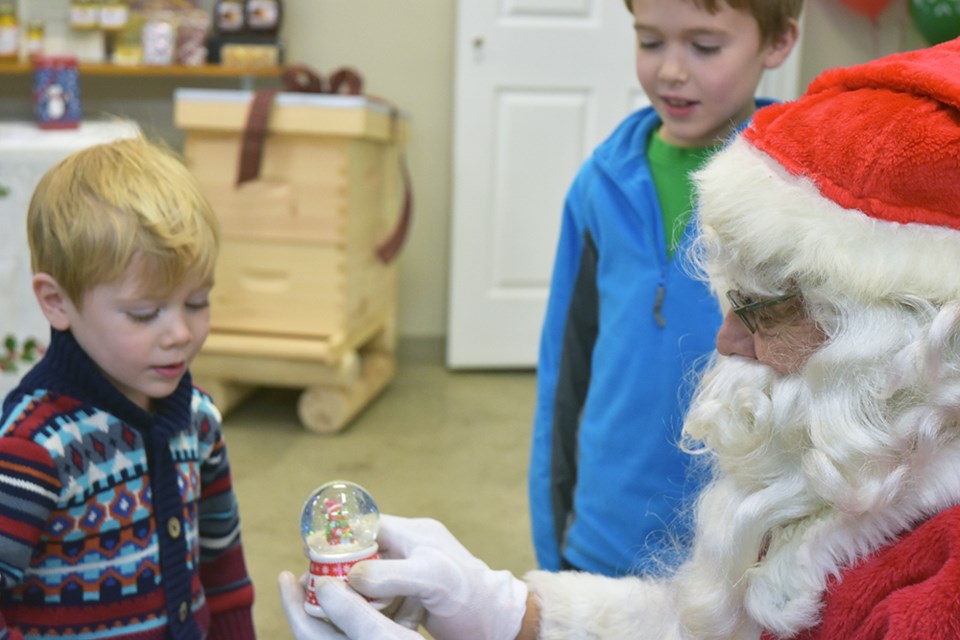 Andrew gives Santa Claus a present, at the Dickey Bee Honey Christmas Open House. Miriam King/Bradford Today