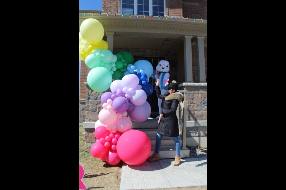 Jen Feeney of Jen Feeney Events stands outside with the Easter Bunny in front of her balloon display. Hillside Photography