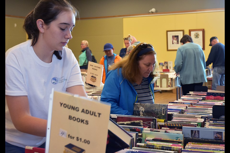 Volunteer adds more books to a display table, at the Friends of the BWG Library Fall Book Sale. Miriam King/BradfordToday