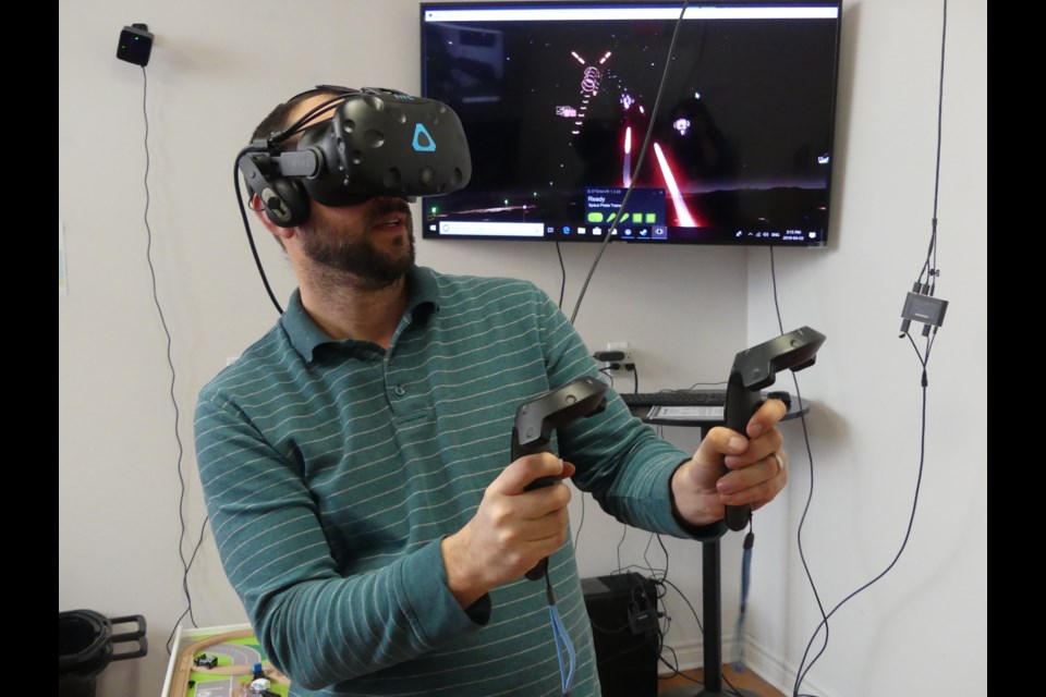 Brian Hayden, co-owner of Experience Toys and Games in downtown Bradford, plays virtual-reality game Space Pirate Trainer, shooting objects out of the sky. Jenni Dunning/BradfordToday