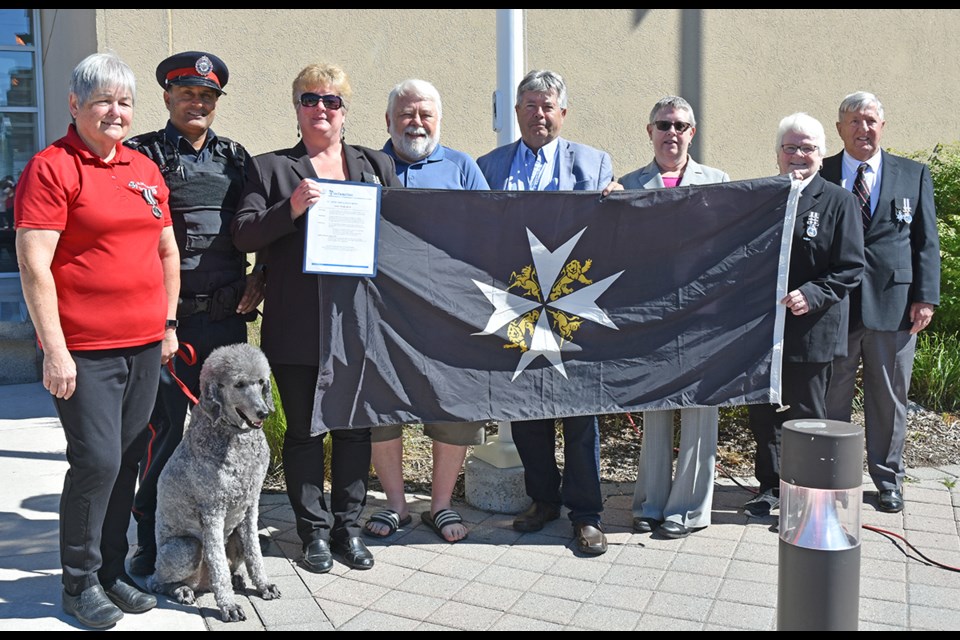 Raising the flag is Vivienne Swarbreck, from left, therapy dog Troy, South Simcoe Police Const. Ranjit Sandhu, Cathy Banting, BWG councillors Gary Lamb and Ron Orr, St. John Ambulance director Lynn Potts, volunteers Claire Campbell and Cam Campbell. Miriam King/Bradford Today