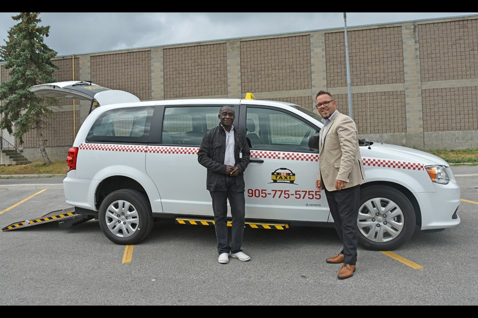Bradford-Bondhead Limousine Taxi Service owner Addai Sarfo, left, and Frank Caietta of Vaughan Chrysler in front of the new accessible cab now on the road in Bradford. Miriam King/BradfordToday