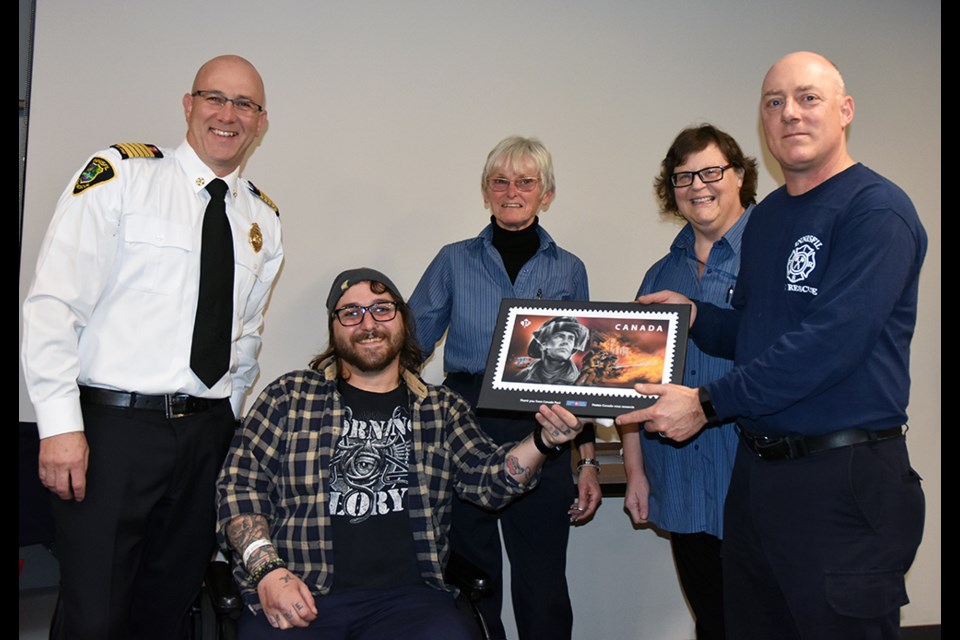 From left, Fire Chief Tom Raeburn joins crash survivor Andrew Gauci as he and Canada Post representatives Laurie Poole and Corinne Mack present a plaque honouring firefighters to Capt. Jason Braida, at Innisfil Fire Station 4 in Cookstown. Miriam King/BradfordToday