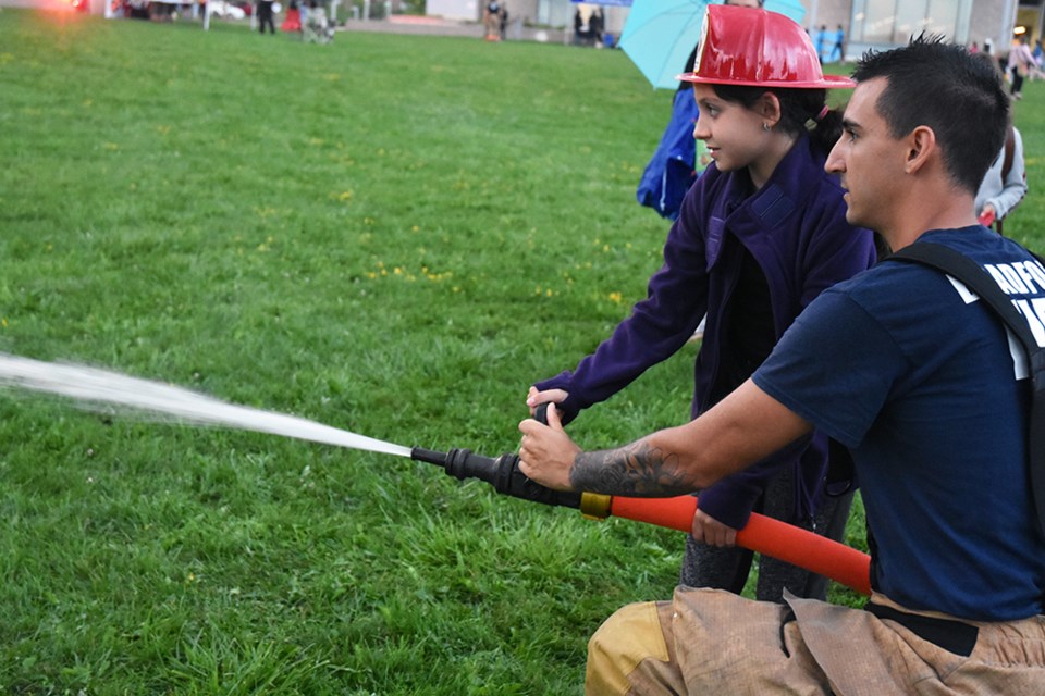 BWG Firefighter Damian Marcangelo shows Sierra how to hold the fire hose to put out pretend flames in a wooden building. Miriam King/BradfordToday