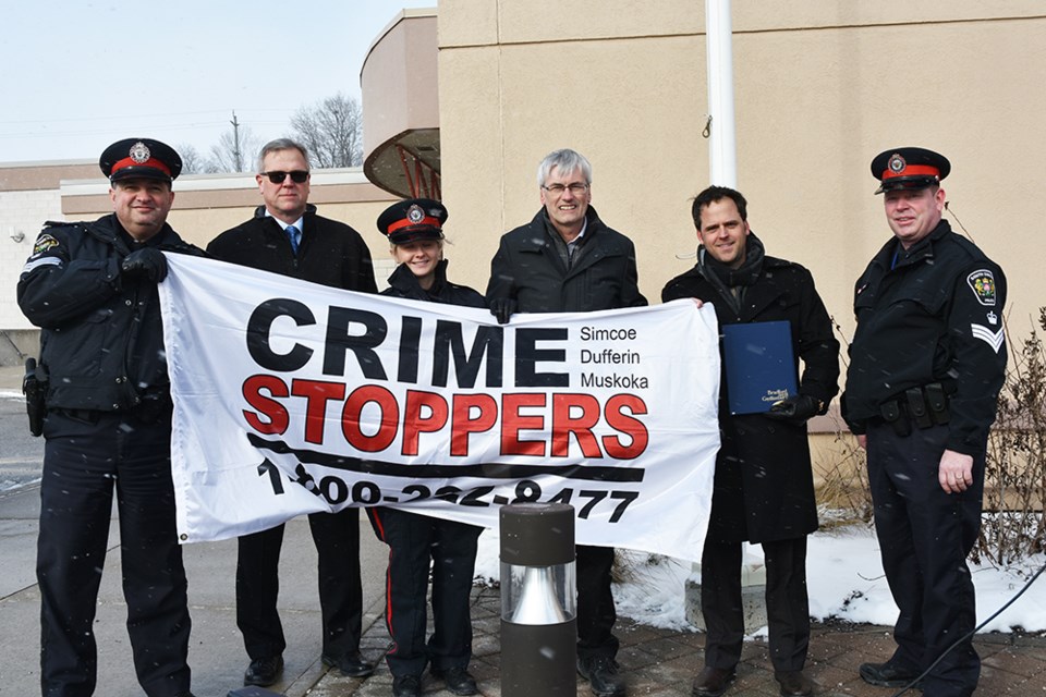 Raising the Crime Stoppers flag from left, South Simcoe Police Sgt. Lew DaSilva, Sgt. Brad Reynolds, Const. Nicole Nielsen, Mayor Rob Keffer, Coun. Peter Ferragine, and Staff Sgt. Steve Wilson, at the Bradford Courthouse, Jan. 10. Miriam King/Bradford Today