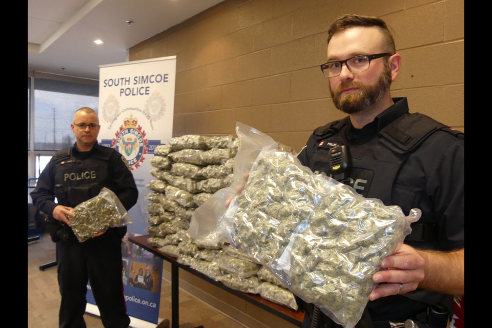 South Simcoe Police Const. Carl Jarvis, left, and Sgt. Dave Phillips with 64 pounds of illicit cannabis they discovered during a RIDE check in Innisfi March 16. Jenni Dunning/BradfordToday