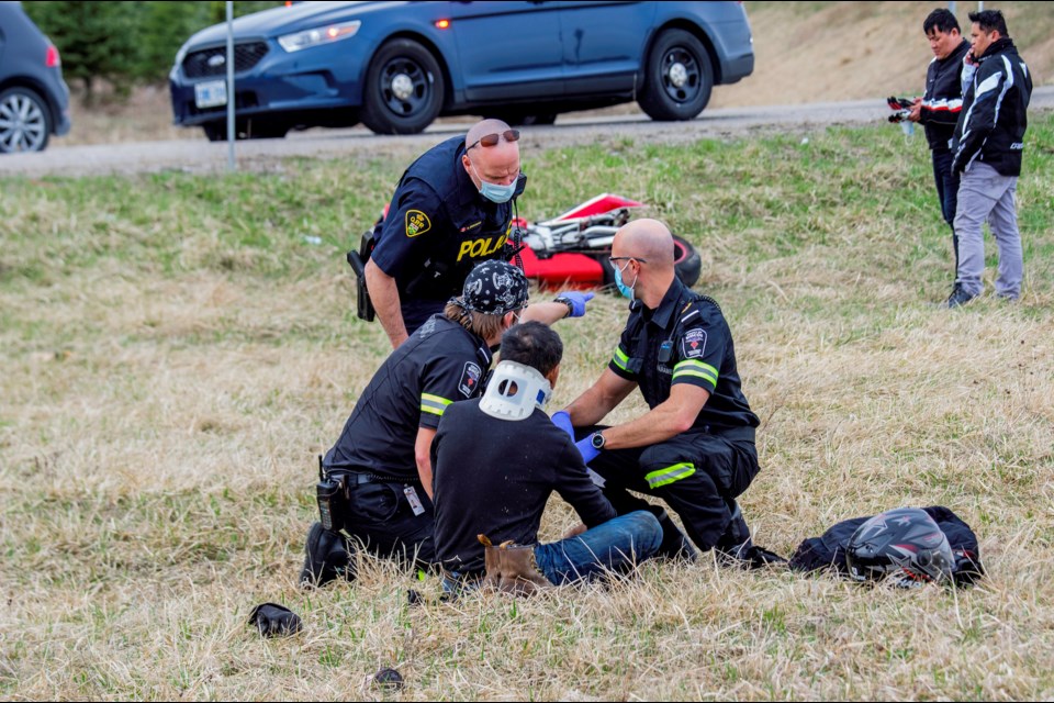 Paramedics attend to the bike rider who was ejected when he failed to maneuvre the turn on the off-ramp from Highway 400, Saturday afternoon. 
