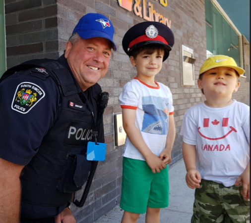 South Simcoe Police Const. Rob Enwright trades hats with a couple Police Week visitors in Innisfil. South Simcoe Police/Twitter