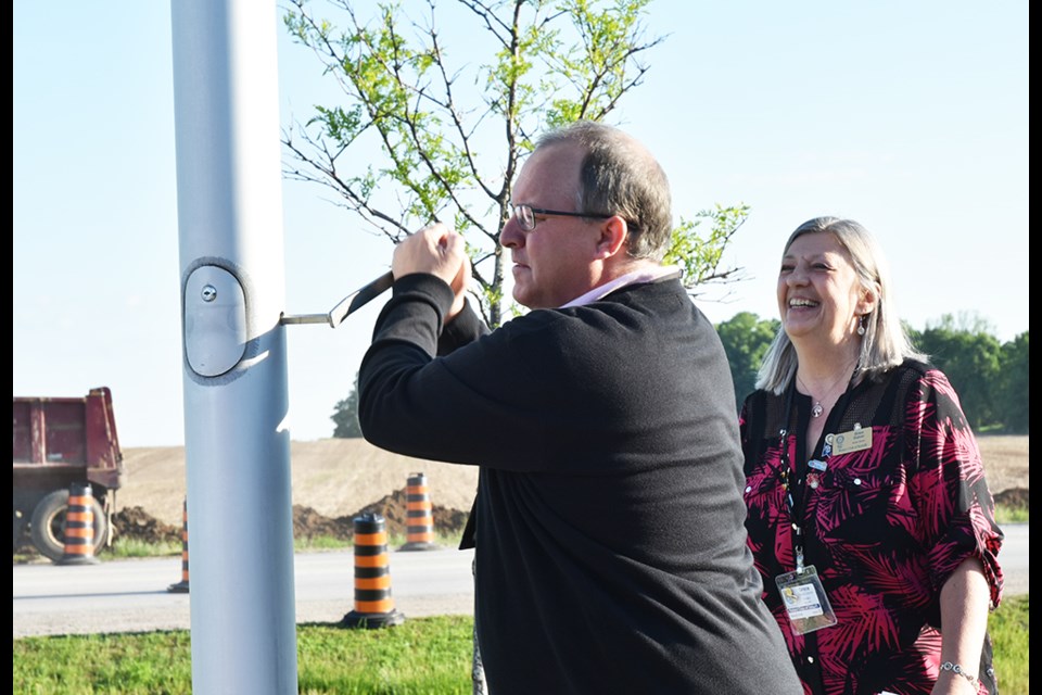 Innisfil Assistant Clerk Kevin Jacobs raises the Rotary flag, as Innisfil Rotary president Grace Doiron looks on. Miriam King/Bradford Today