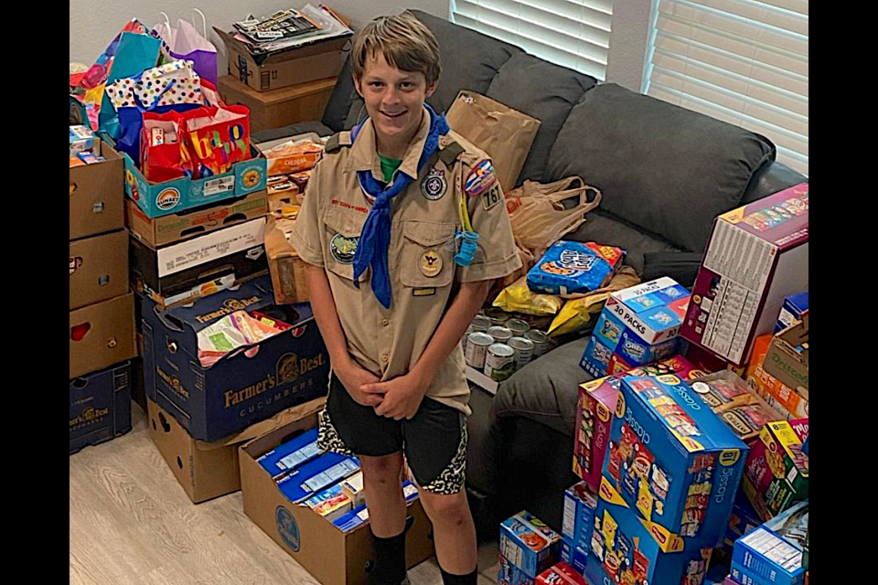 Dylan Dunnington stands among mounds of food donations collected earlier this month for Broomfield FISH.