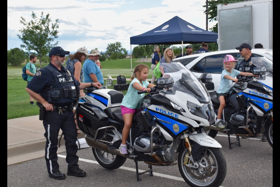 Underage drivers sit atop police motorcycles during the National Night Out event in Broomfield on Tuesday.