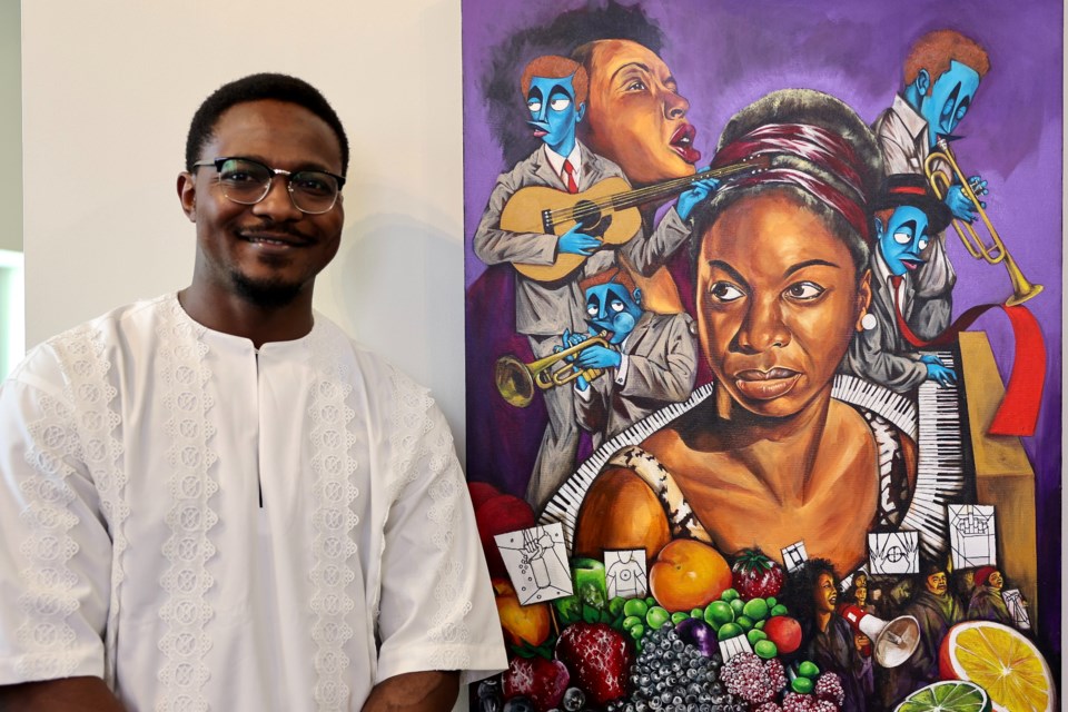 Komi Olaf poses with his piece, Strange Fruit, which was awarded first place in the Emancipation art exhibition at Helson Gallery.