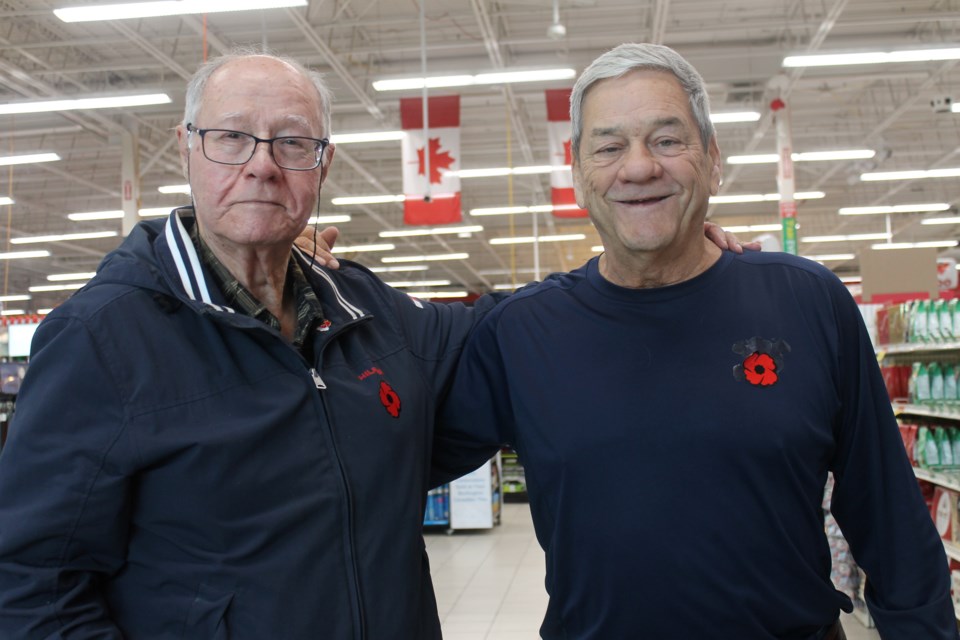 Burlington resident Brian Thorpe (left) purchases a poppy from Legion Br. 60 volunteer Réal Caron at the Canadian Tire on Fairview Street on Nov 3.
