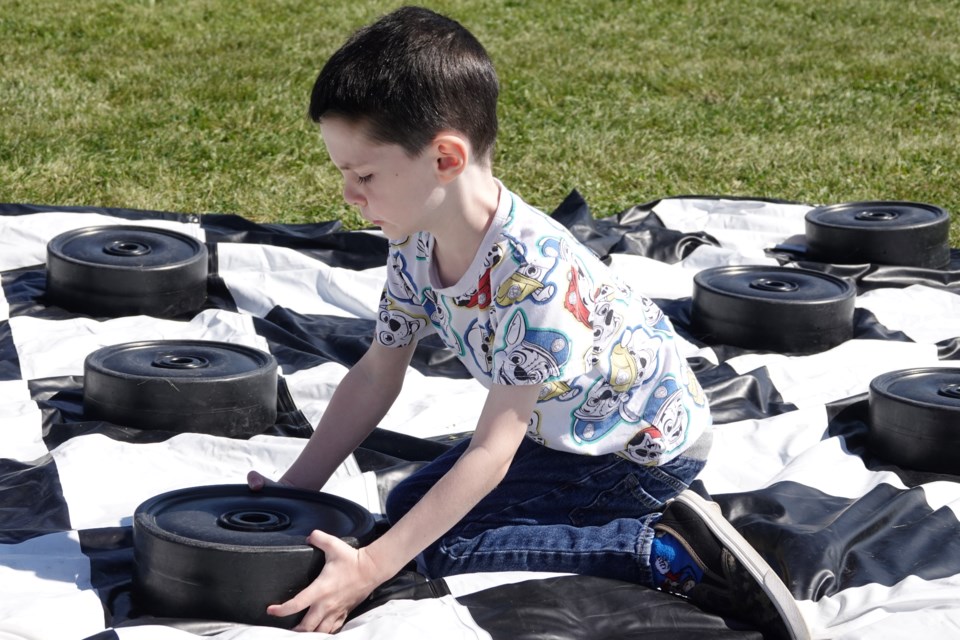 Nolan Kozak, five, learns how to play checkers during the Orchard Community Picnic Saturday.