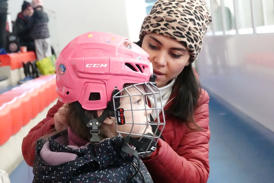 Paola Sullivan adjusts her daughter Isabella's helmet.