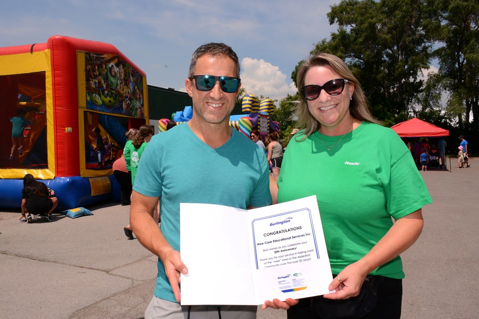 Councillor Kelvin Galbraith delivers congratulations from the City of Burlington to Jennifer Nettleton, who co-owns Aldershot's Wee Care child care centre with Jason Hall (absent). Wee Care marked their 20th anniversary in the community day with an afternoon of family activities on Sunday, June 25