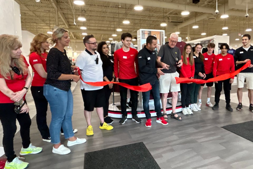 Councillor Paul Sharman does the honours at the ribbon cutting to unveil the renovated Sport Chek store at Appleby Crossing on Saturday.