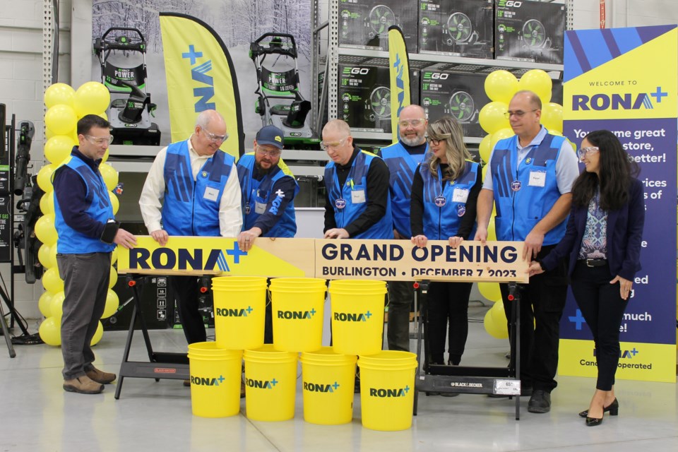 Cutting the board to launch the new RONA+ in Burlington were Marc Macdonald, Paul Faulds, Peter Bingleson, Doug Jack, Steve Bartu, Sheri Cooper and Justine Low.