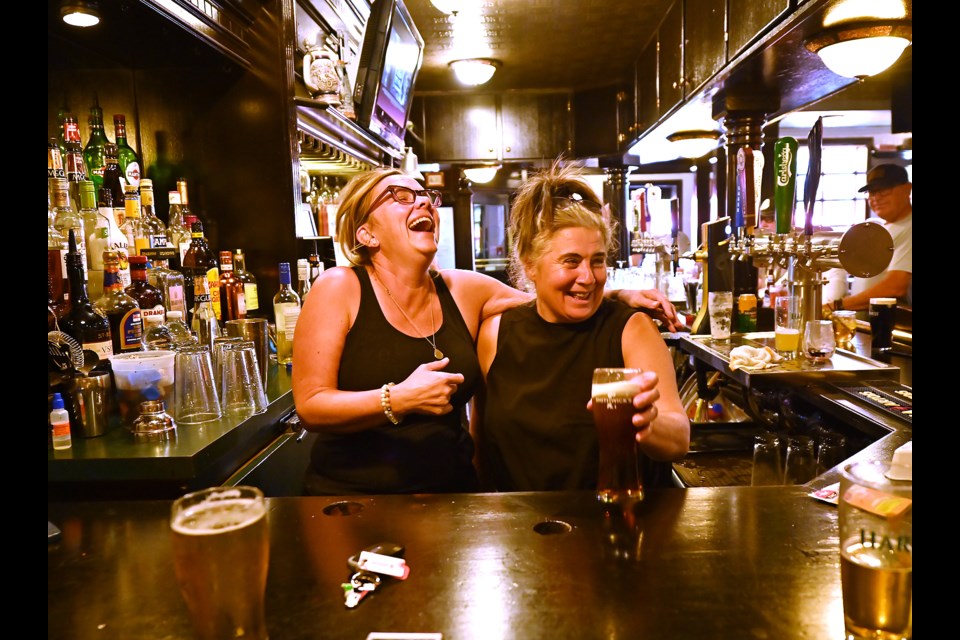 Longtime bartenders Sue Gibson (26 years) and Amanda Scolfield (28 years) ham it up for the camera during their final shift at The Queen's Head Pub.