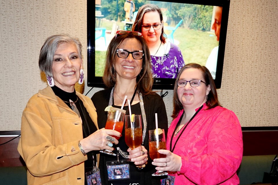 (Left to right) Cathy Starfire, Indigenous psychic medium, Melinda Paletta, owner and executive producer of Basil and Sage Inc., and Leah Strocen, psychic and medium, enjoy cocktails at the Feb. 18 launch at the Holiday Inn Alloro Restaurant of Basil and Sage TV, a new show about cooking and mediumship. The show is playing in the background.