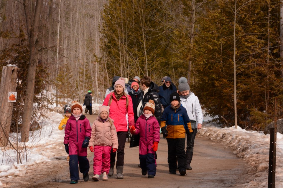 Guests walk into the sugar bush area during a March Break visit to Mountsberg's Maple Town.
