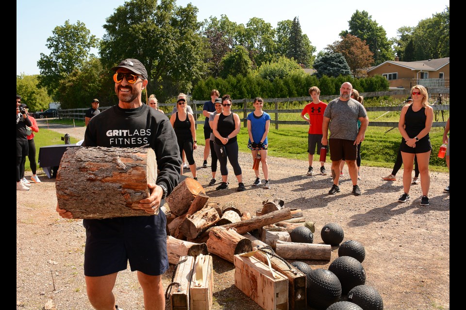 Coach Peter D'Amore lifts a log over his head to demonstrate the next event will be at the Gritlabs boot camp Saturday morning.