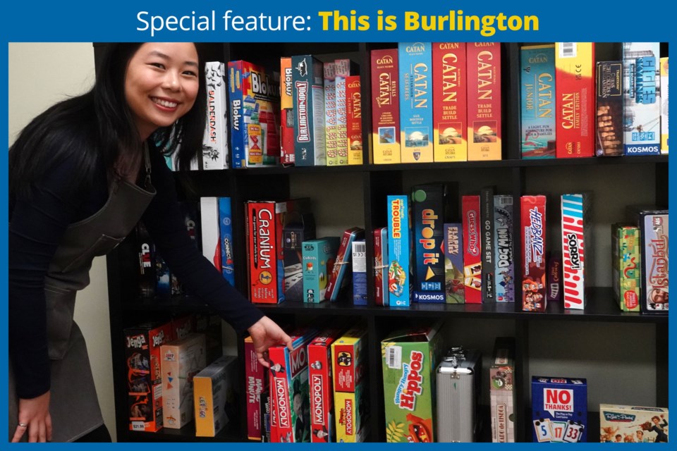 Sophia Zeng arranges some of the board games on the shelves at the Nostalgia Games Café, which she runs with her husband, George.