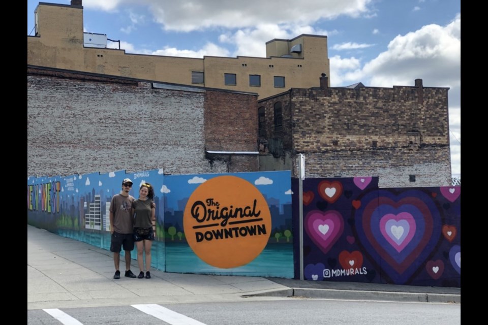 Artists Ela Maftei and Mihai Darvasa of MD Murals posed beside a colourful, three-sided mural they did for the Downtown New West BIA in the spring of 2020 - where one side reads #TogetherNewWest