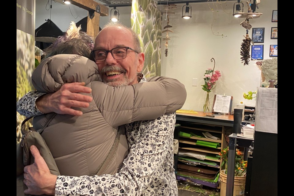 Robin Schafer, owner of Bunches and Blooms, gets a hug from a longtime customer, after learning the shop is closing in March.