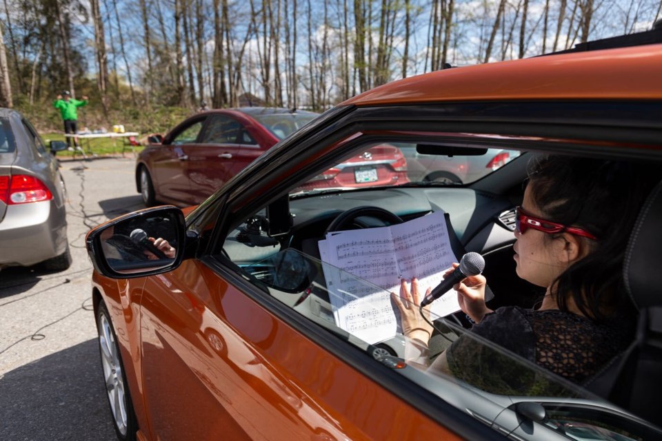 Singers rehearse safely in their cars, with microphones feeding to a mixing board and an FM transmitter broadcasting the group to all participants, during a Vancouver Thunderbirds "carbershop" chorus rehearsal.
