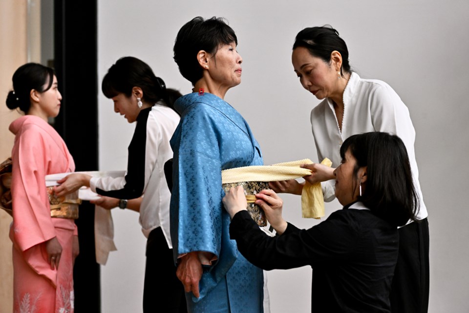 Skilled assistants, under the guidance of Fumiko Horan (kimono technician for Shōgun) dress models Saiko (right) and Yurina in kimono during the Nikkei Centre’s month of O-Hanami cultural celebration.