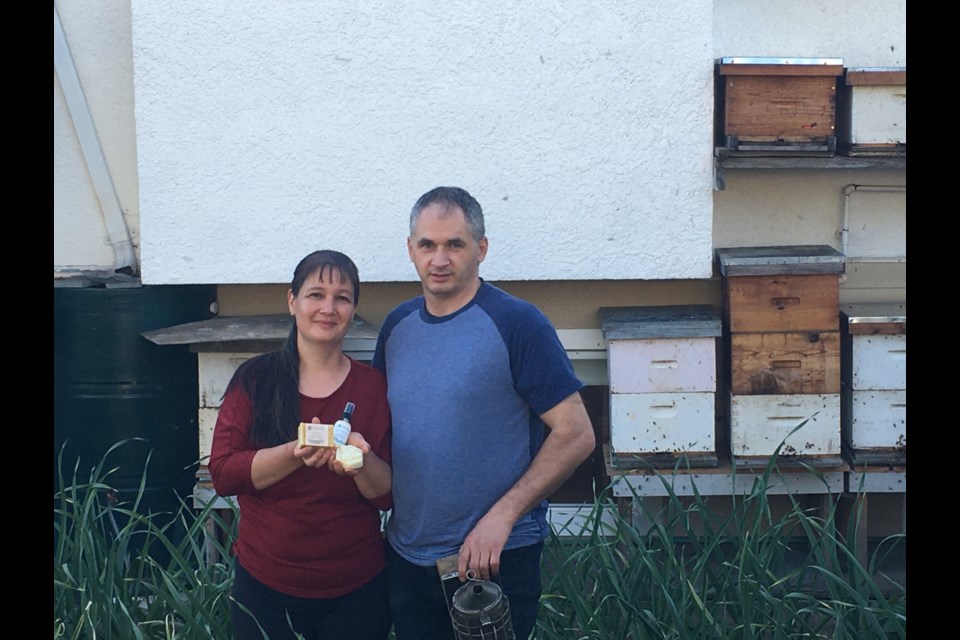 Agnes and Laszlo Kalmar in their backyard garden with their beehives.