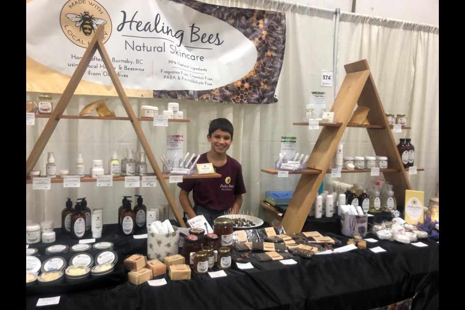 Agnes and Laszlo Kalmar's son at Healing Bees Natural Skincare booth at a craft fair.