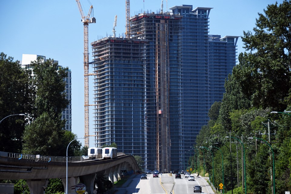 A wall of condo towers under construction in Brentwood town centre dwarfs cars on Lougheed Highway in Burnaby.