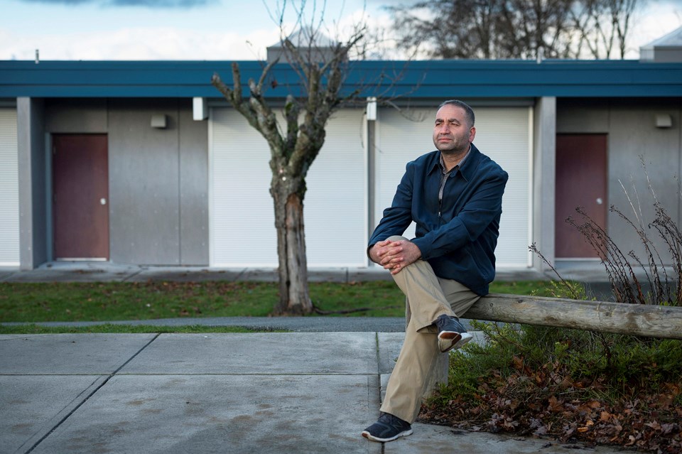 Abdul Mujeeb Khalvatgar, a veteran journalist who fled Afghanistan with his family in August, sits outside of his children's new school.