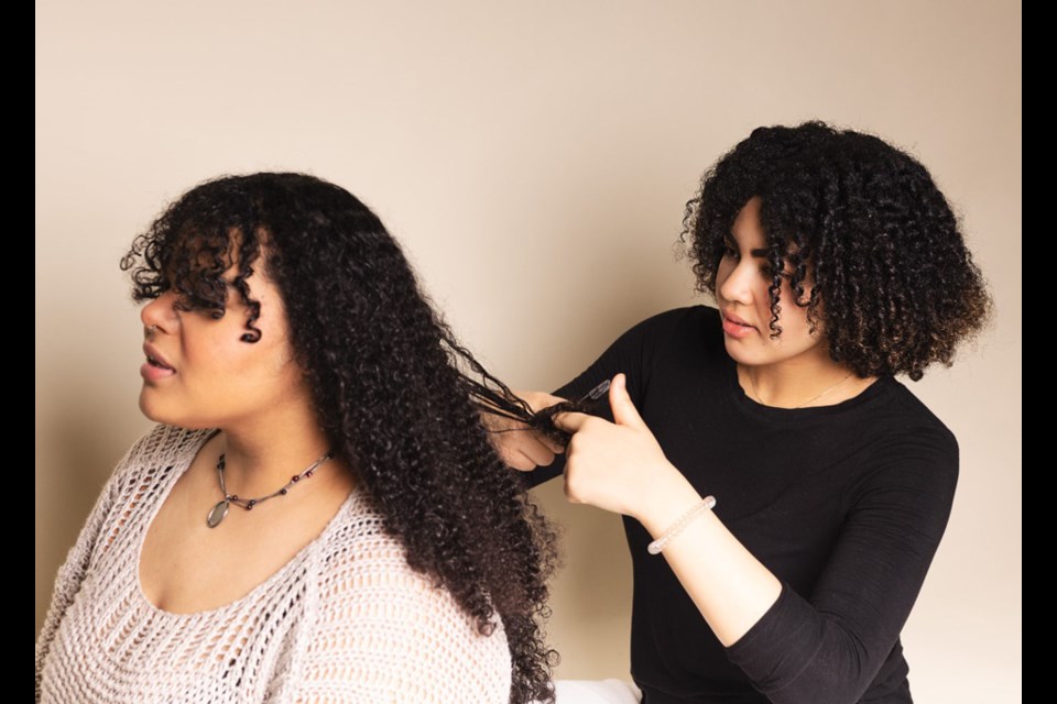 Burnaby Mountain Secondary Grade 12 student Sarah Lennon styles Grade 11 student Chinaka Mayes’s hair. This image was part of a photography display titled Black Hair is Art during Black History Month in February.