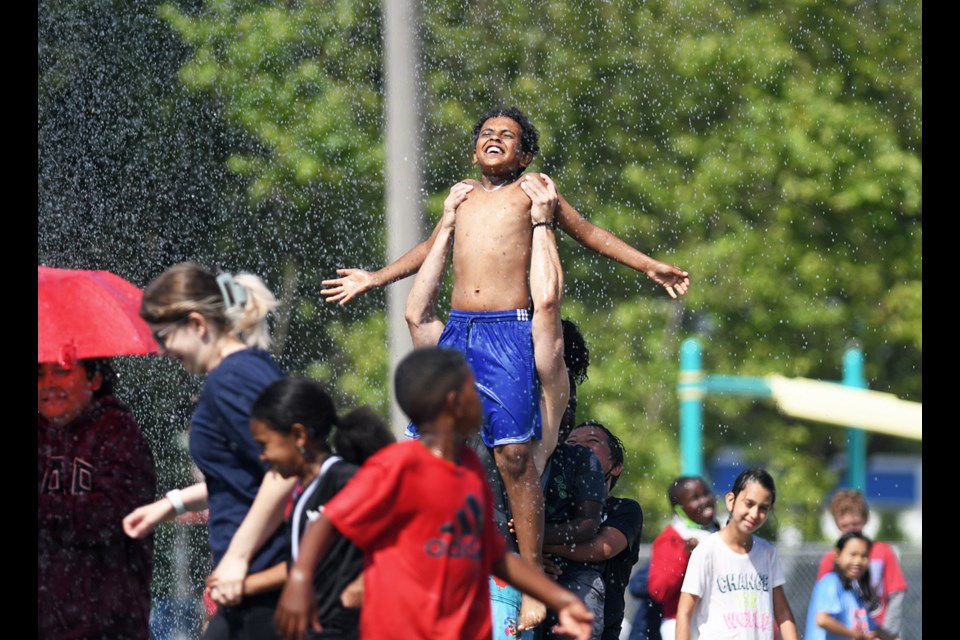 Summer school students gather on the field at Burnaby's Edmonds Community School for a drenching from a fire truck.