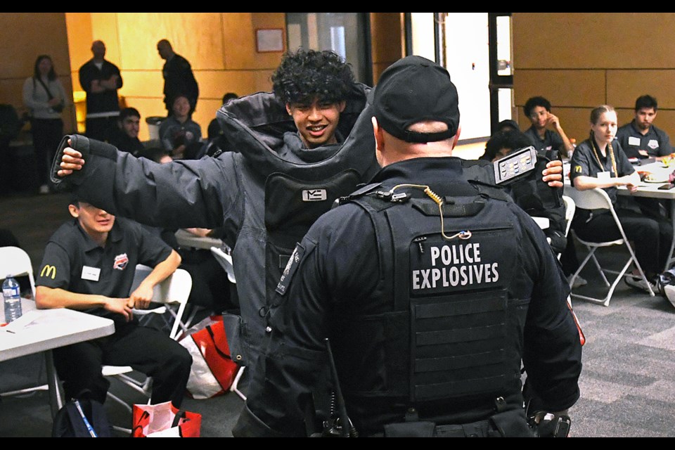 RCMP bomb disposal expert Const. Greg Copeland helps Byrne Creek Community School Grade 12 student Muhammad Safrizal don a bomb suit at the Burnaby RCMP youth academy Wednesday. 