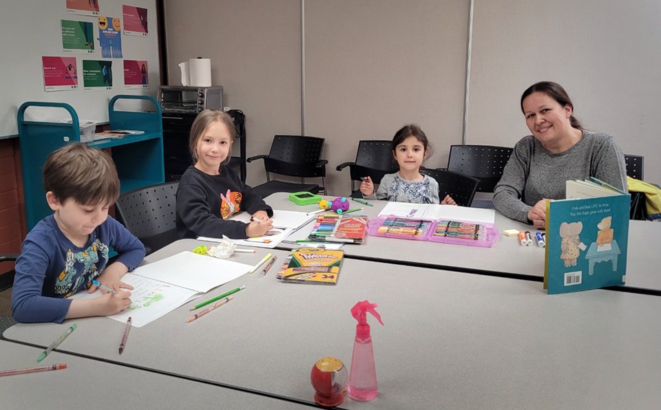 From left, Iliia P., Anastasiia K. and Alisa K. join Armstrong Elementary teacher Iuliia Sukhina-Volkova at a reading club for Ukrainian refugee children at the Cameron branch of Burnaby Public Library. 